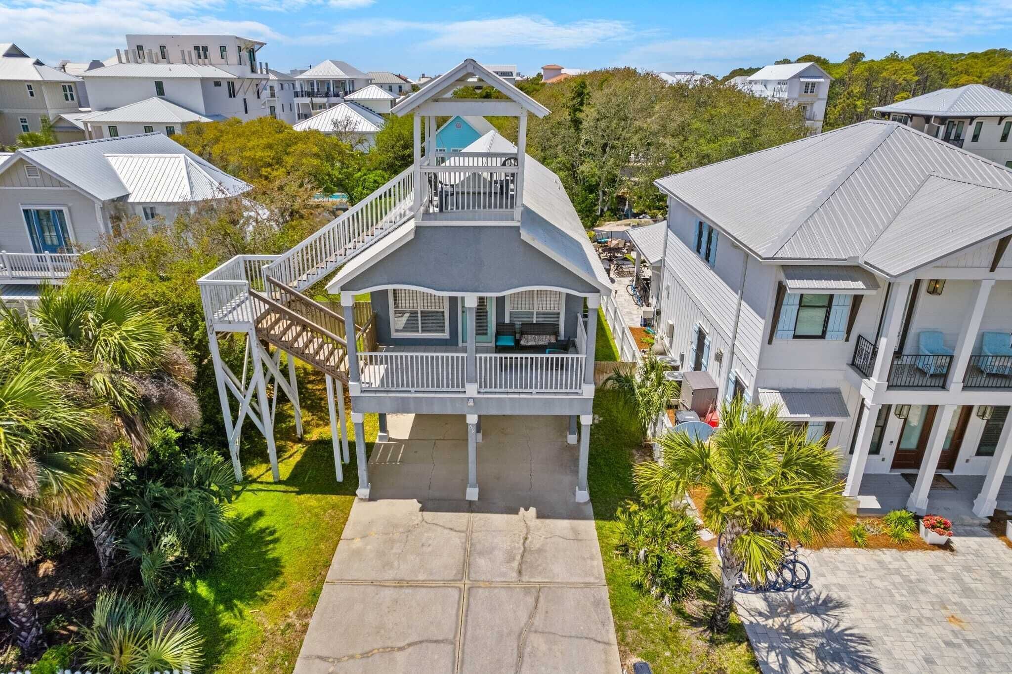 A coastal residential area with houses featuring balconies and a central building with a staircase leading to a deck.