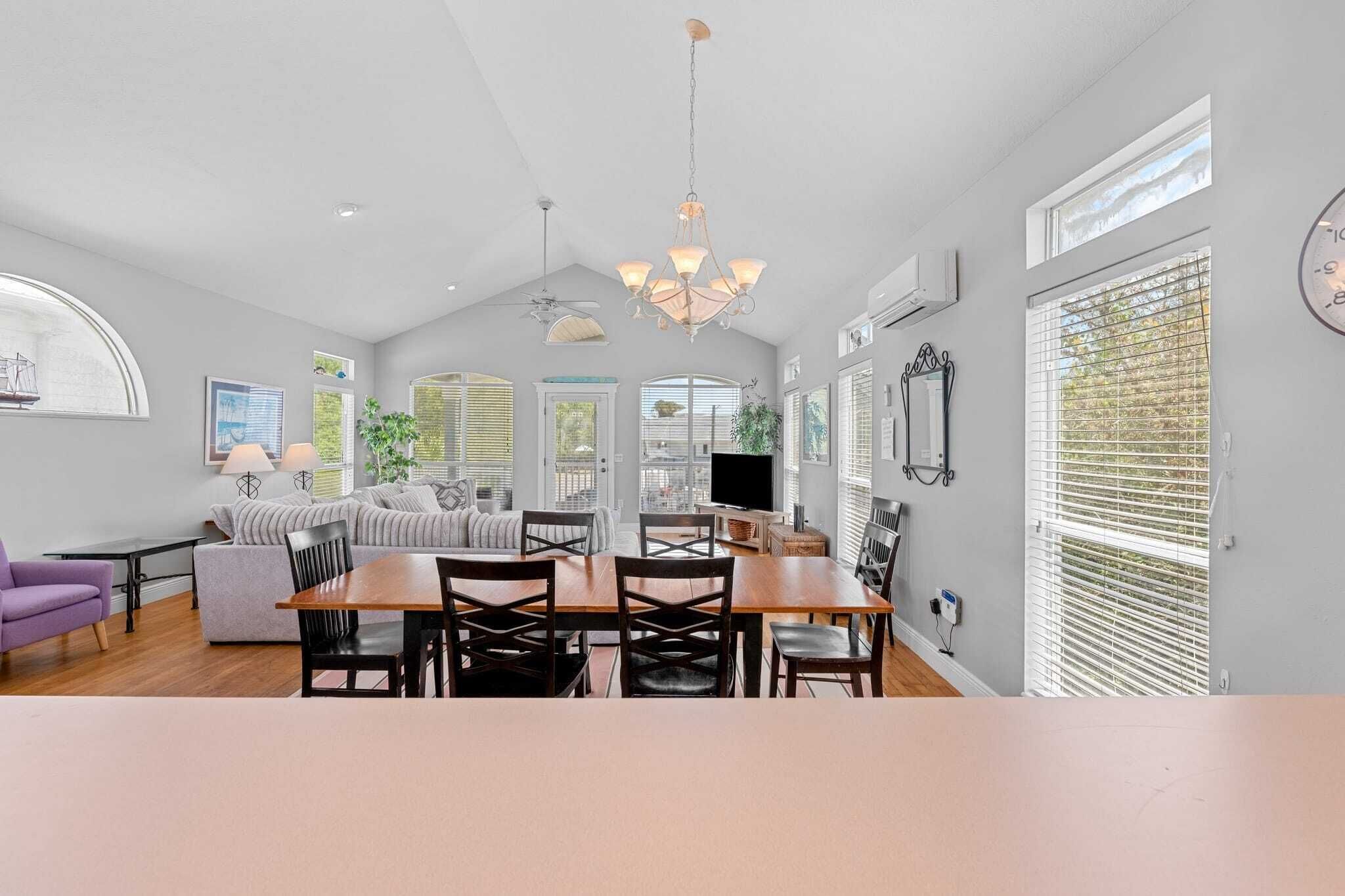 A spacious living area with a dining table, chairs, a sofa, and a television.