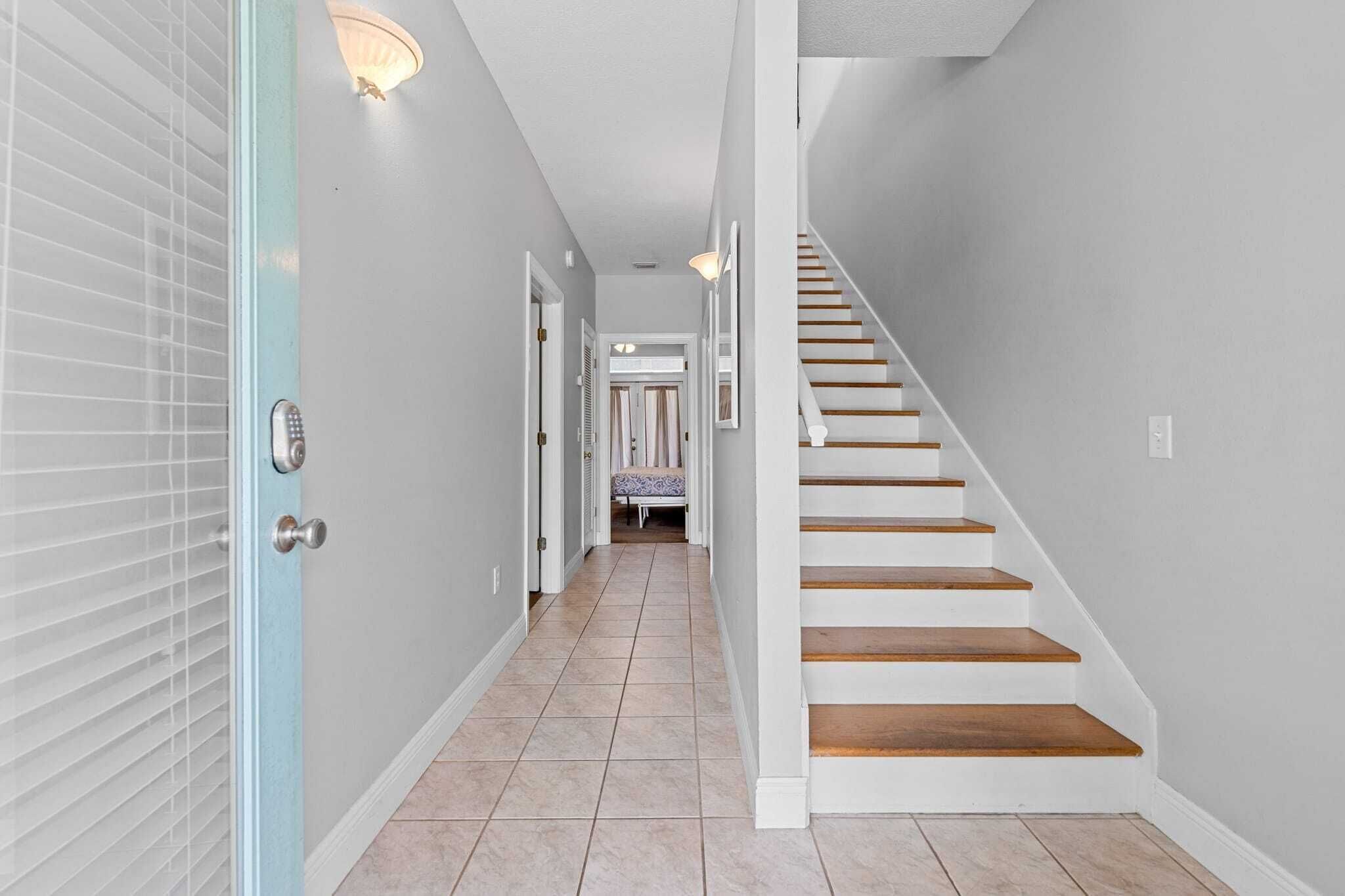 Un couloir avec un escalier menant à une chambre.