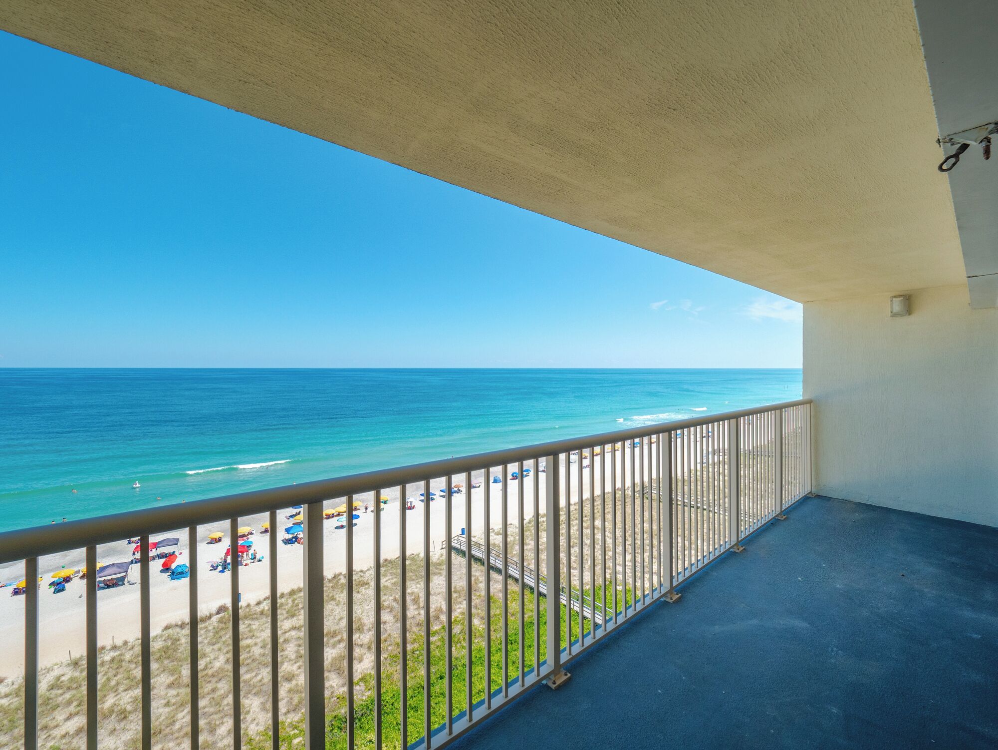 A balcony with a view of the beach and ocean.