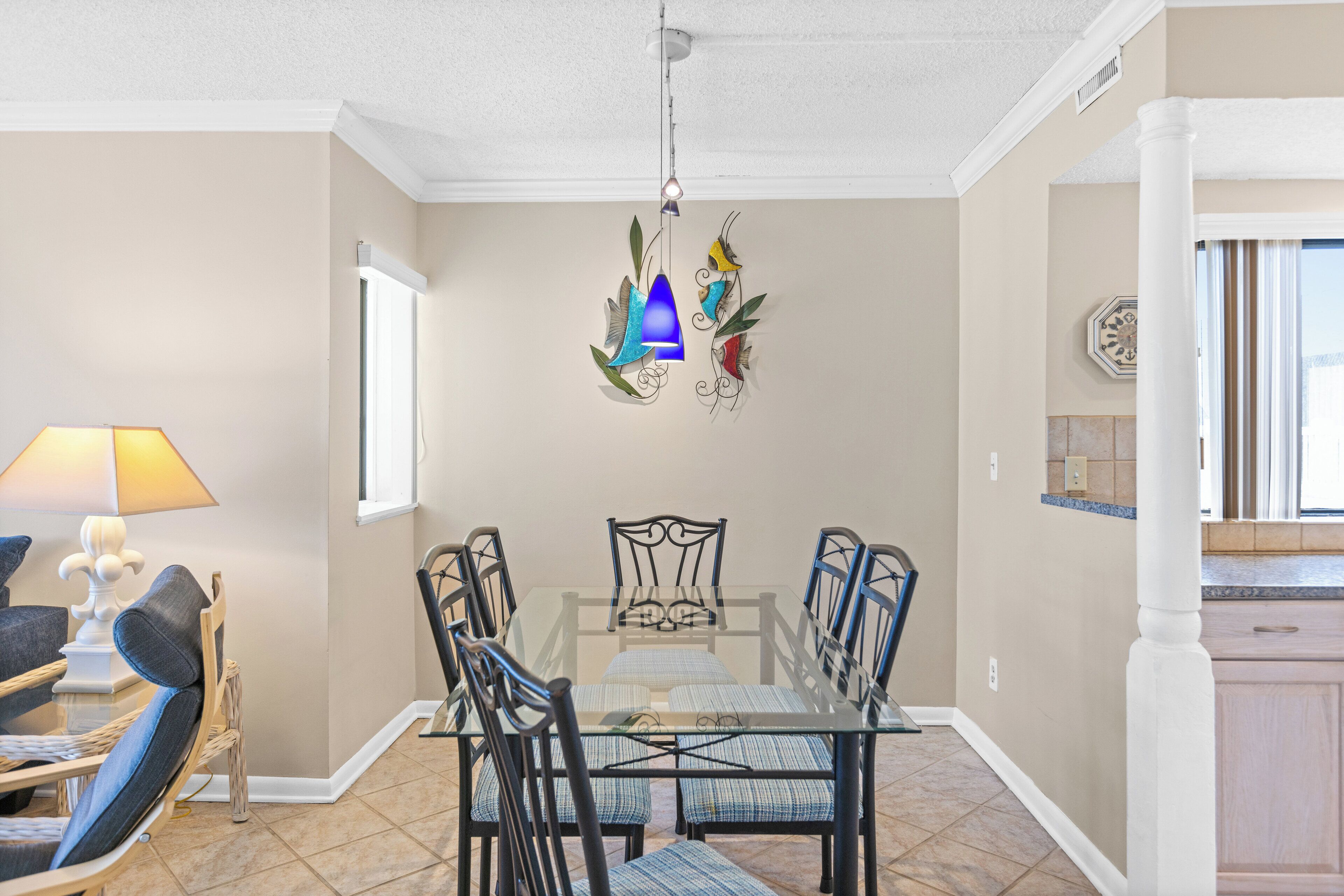Un comedor con una mesa de vidrio, sillas de metal y una lámpara colgante decorativa.