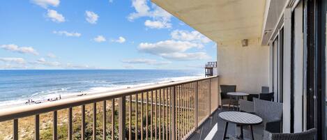A balcony with a view of the beach and ocean.