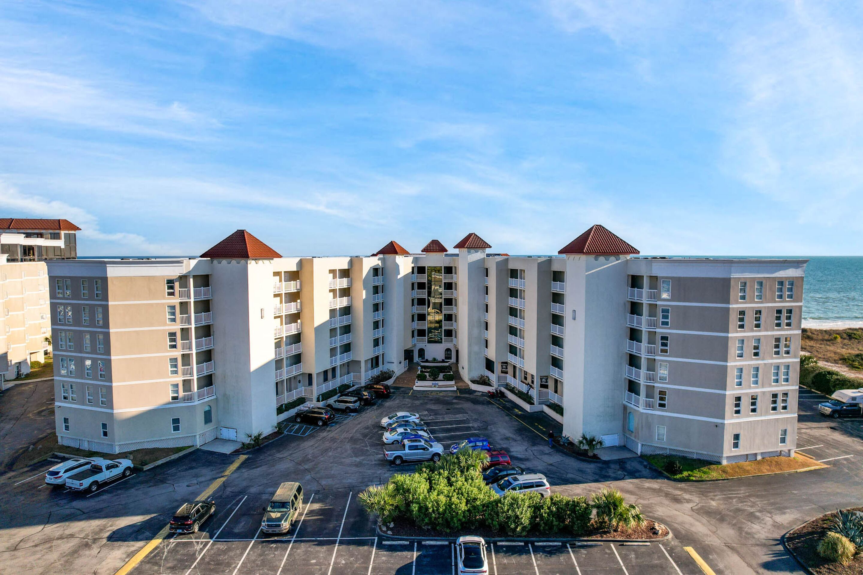 Un hôtel à plusieurs étages doté d’une cour intérieure, d’un parking et offrant une vue sur l’océan.