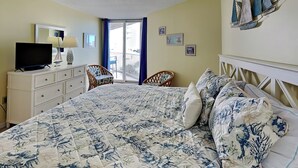 A hotel room with a bed, a television, a dresser, and a balcony with a view. - St. Regis by Carolina Retreats (Sneads Ferry)