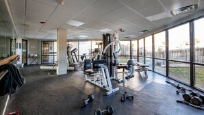 A gym with various exercise equipment, large windows, and a view of the outdoors. - St. Regis by Carolina Retreats (Sneads Ferry)