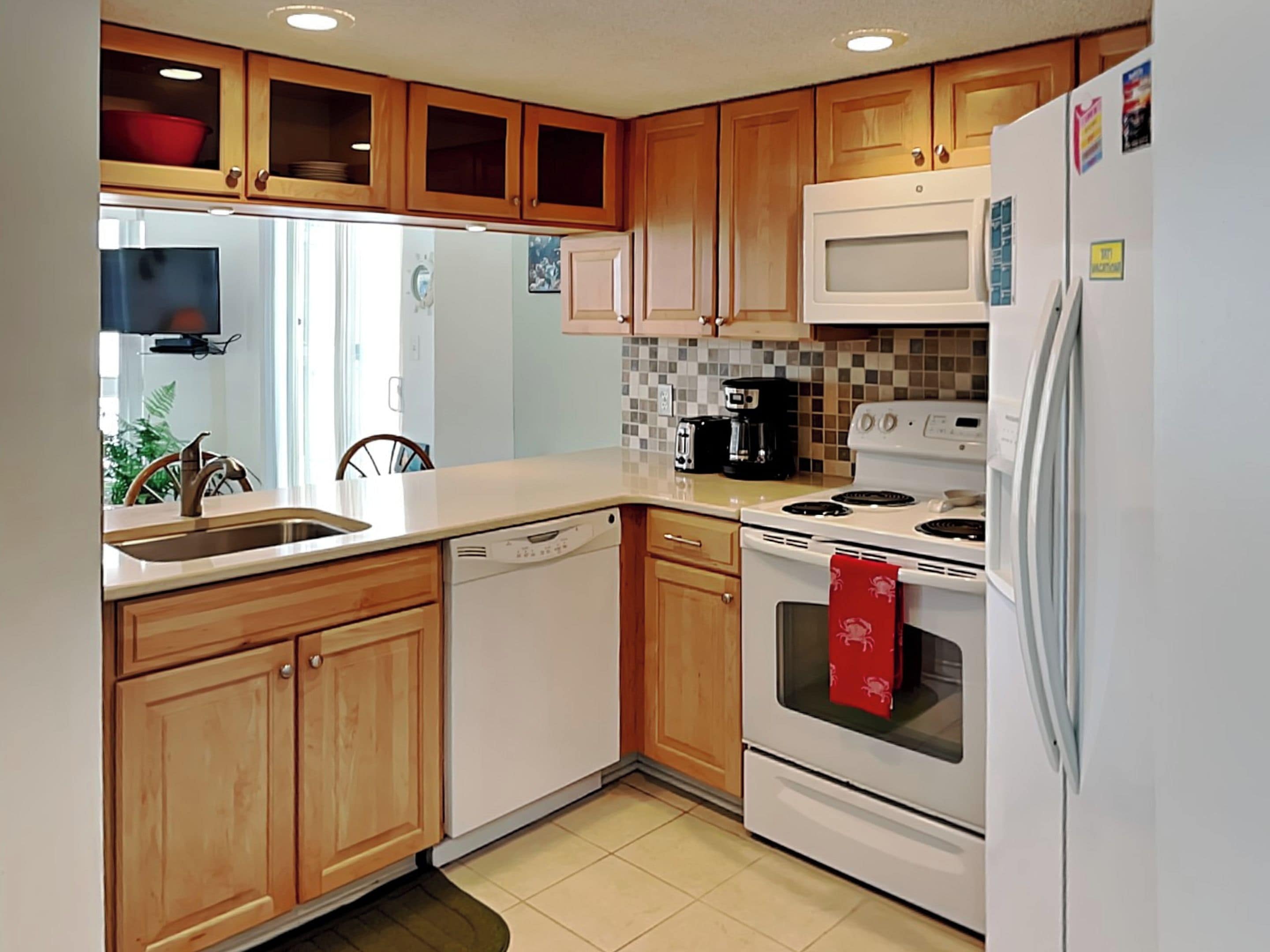 A kitchen with wooden cabinets, a white refrigerator, a stove, and a dishwasher.