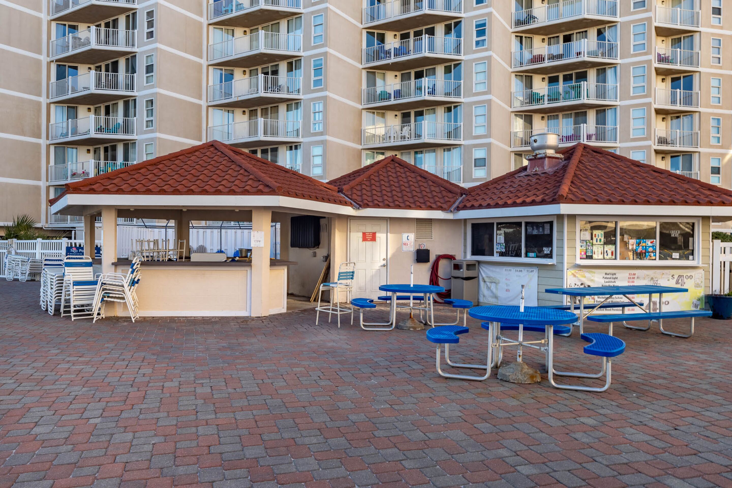 A courtyard with outdoor seating, a kiosk, and a building with multiple balconies.