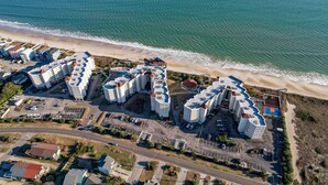 An aerial view of a coastal hotel complex with multiple buildings, parking areas, and a beach. - St. Regis by Carolina Retreats (Sneads Ferry)