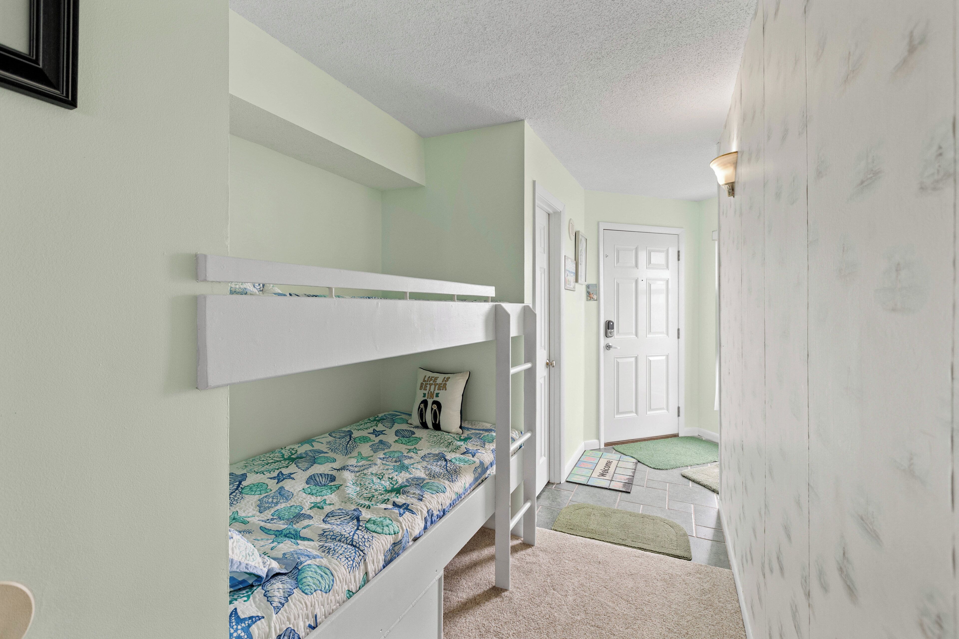 A bedroom with bunk beds, a door, and a hallway.
