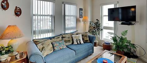 A living room with a sofa, a coffee table, a TV, and a lamp.