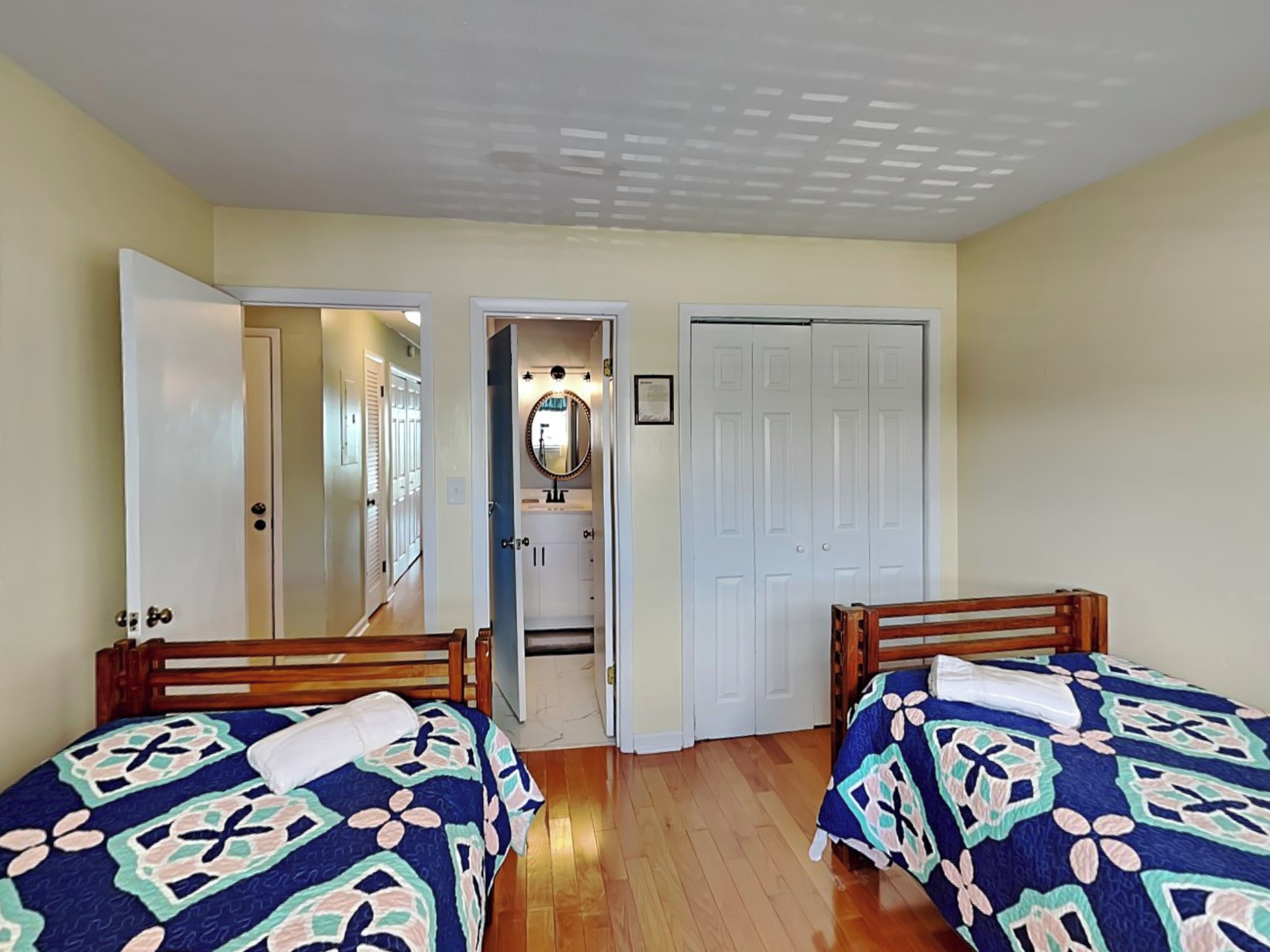 Une chambre avec deux lits, une salle de bain avec un miroir et un placard.