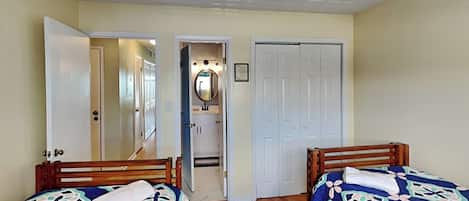 Une chambre avec deux lits, une salle de bain avec un miroir et un placard.