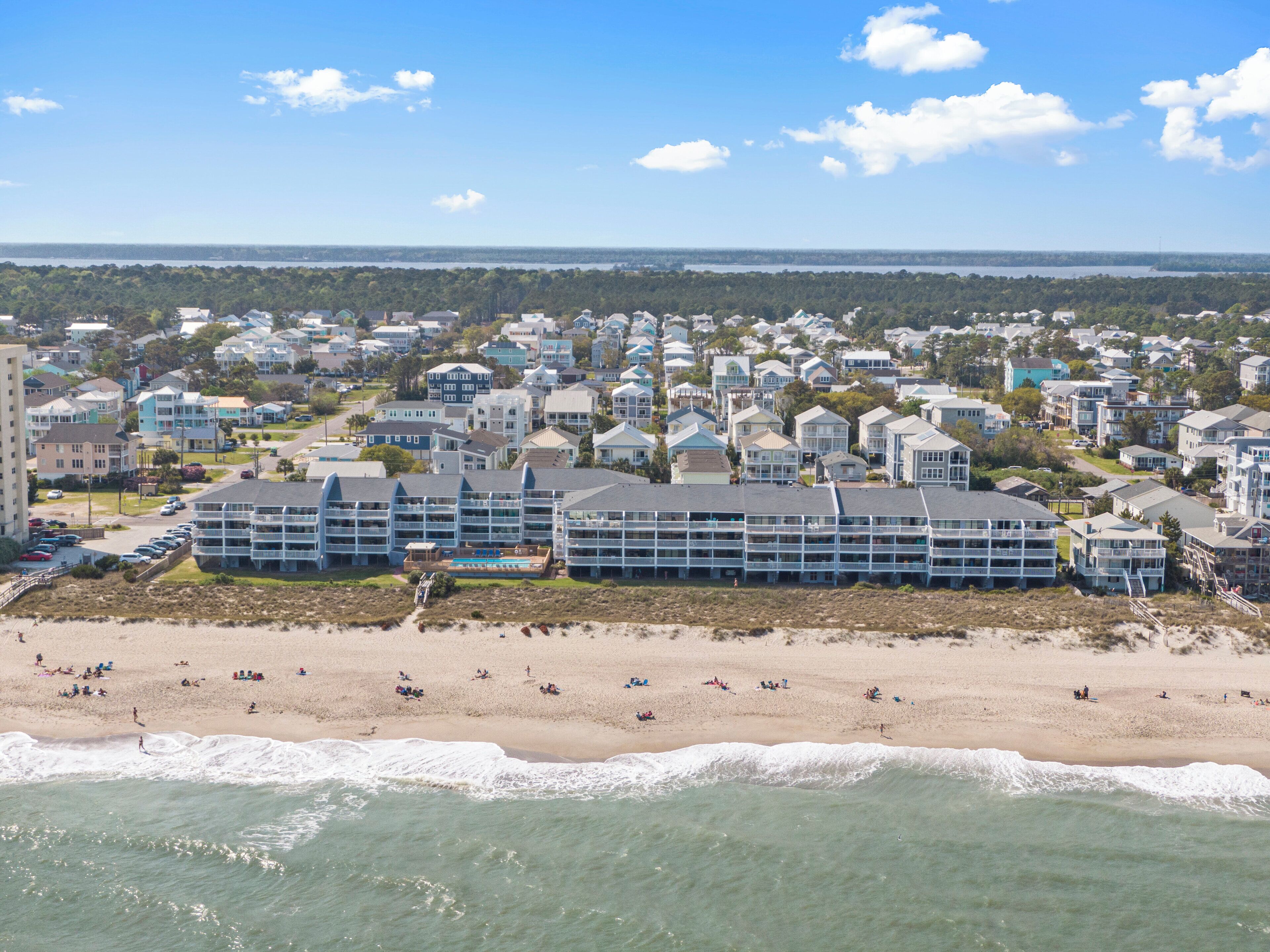 Un hotel costero con varias construcciones, una playa y vistas al océano.