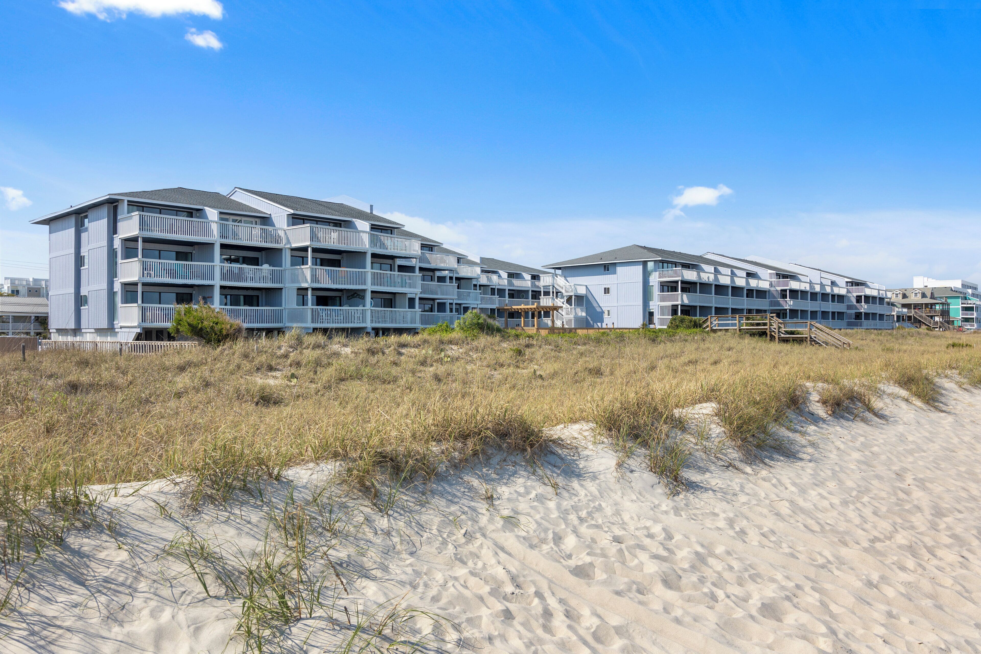 Un hôtel situé en bord de mer, doté de nombreux balcons et donnant sur une plage de sable.