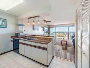 Enjoy cooking in this well-equipped kitchen with a central island, sink, and microwave, overlooking a scenic ocean view.