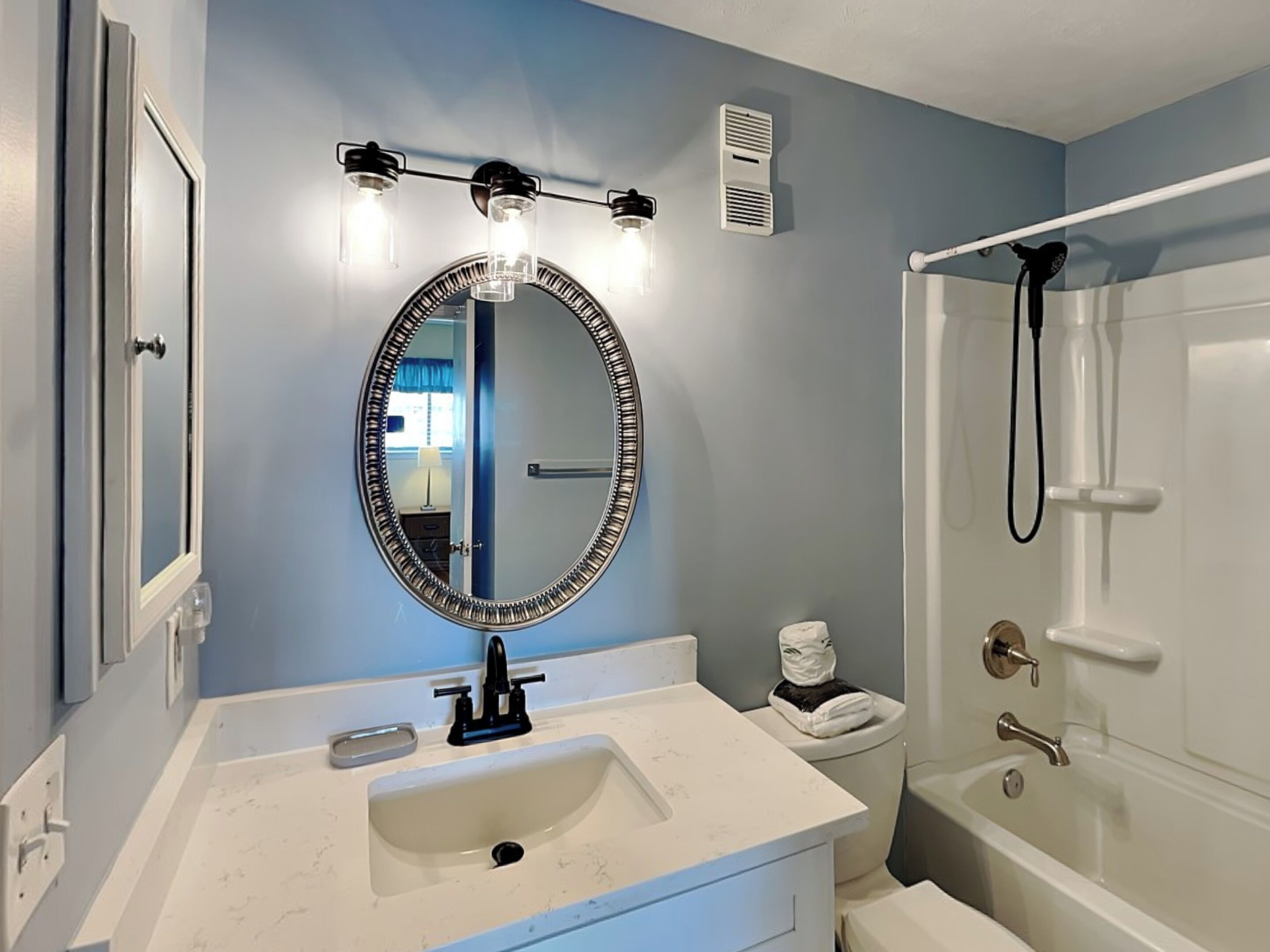 A bathroom with a sink, mirror, toilet, and shower.