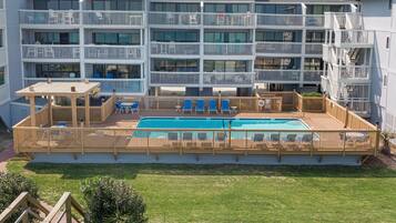 A multi-story hotel with a pool area, outdoor seating, and a well-maintained lawn.