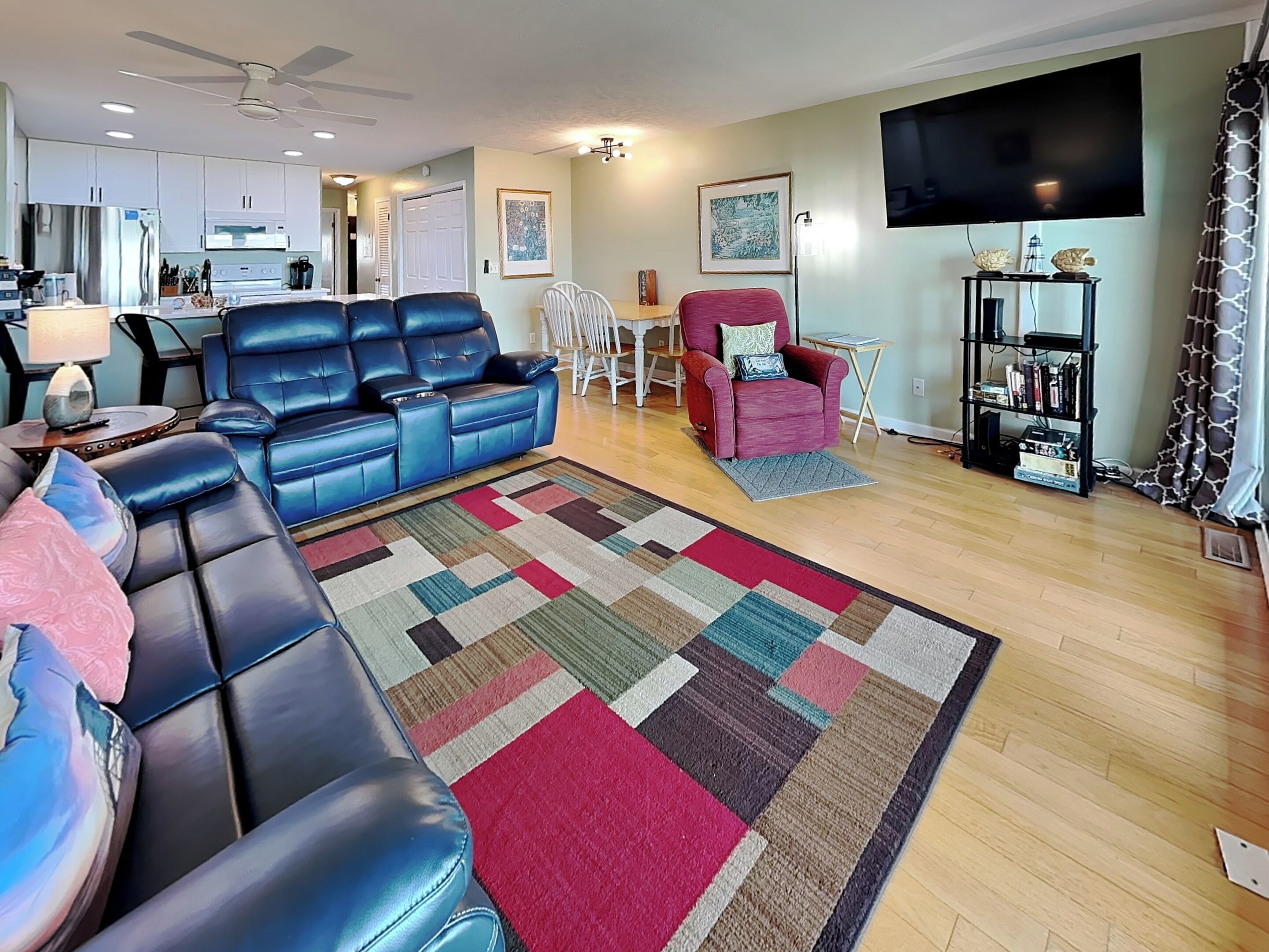 A living room with a blue leather sofa, a red armchair, a wooden coffee table, and a TV.