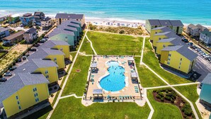 Ein Resort mit einem zentral gelegenen Pool, direktem Strandzugang und mehreren Gebäuden mit Balkonen.