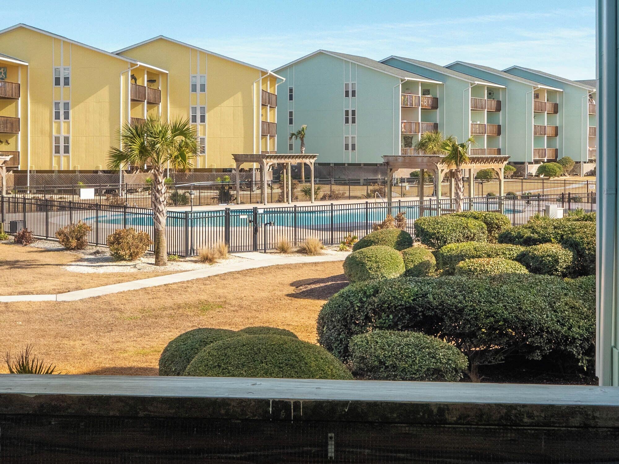 A hotel with multiple-story buildings, a swimming pool, and well-maintained landscaping.