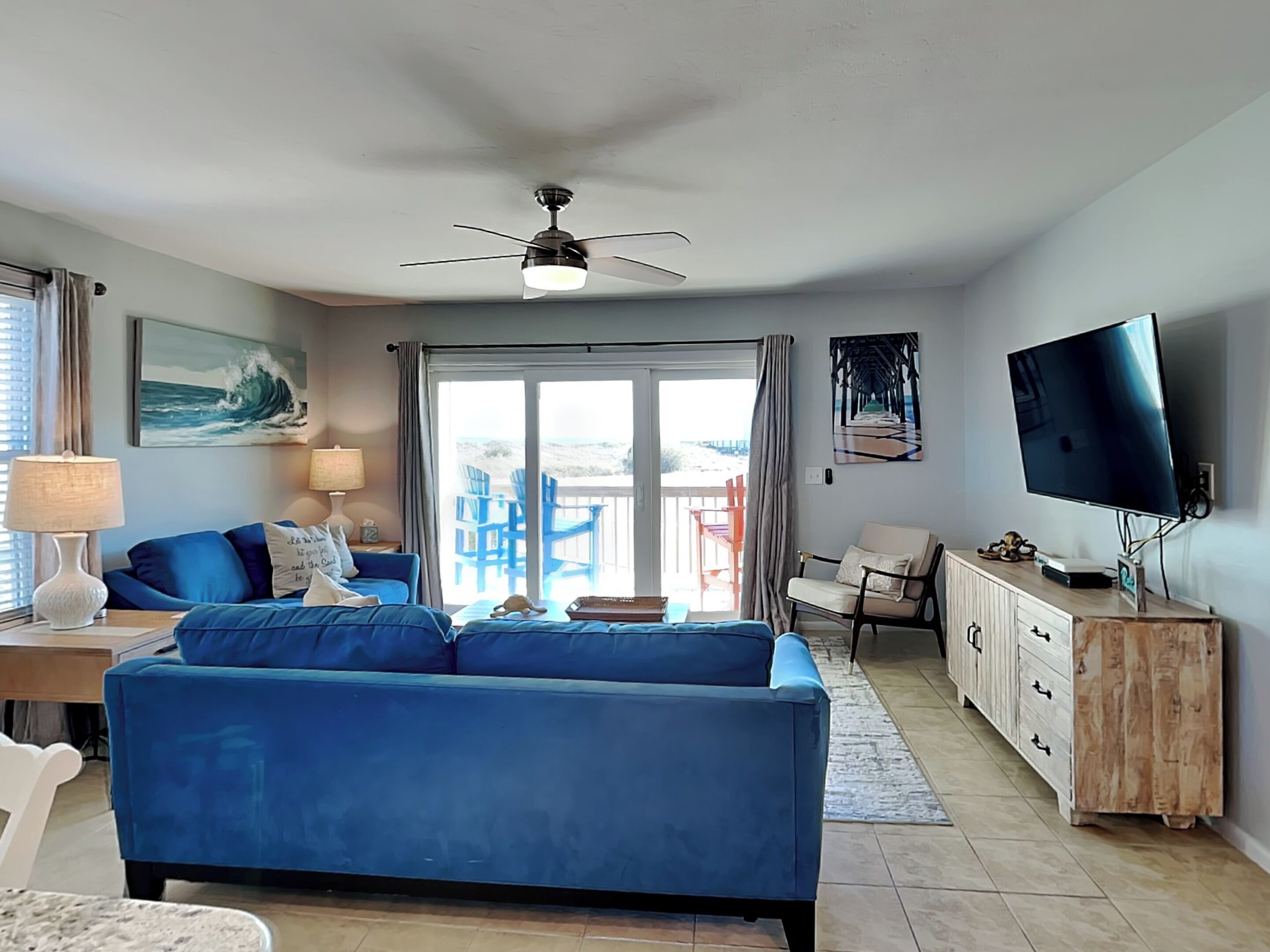 Ein Wohnzimmer mit blauem Sofa, Fernseher und Deckenventilator.