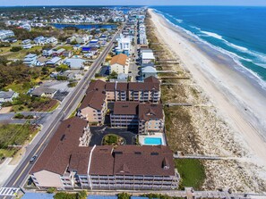 Vista aérea de un hotel costero con varias edificaciones, una playa y una carretera.