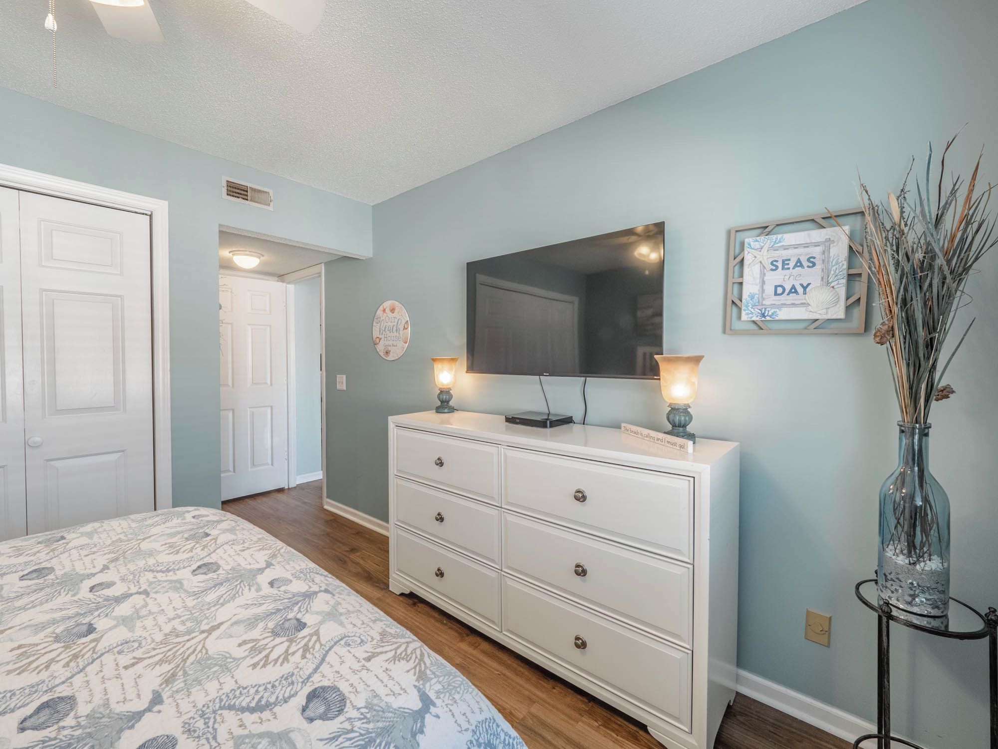 Un dormitorio con cama, cómoda y televisor en la pared.