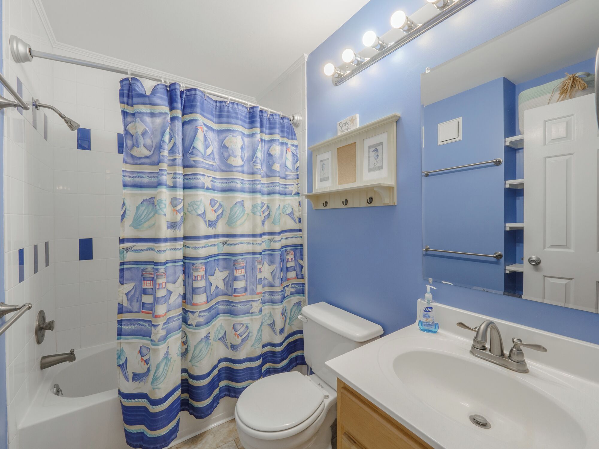 A bathroom with a shower curtain, toilet, sink, and mirror.