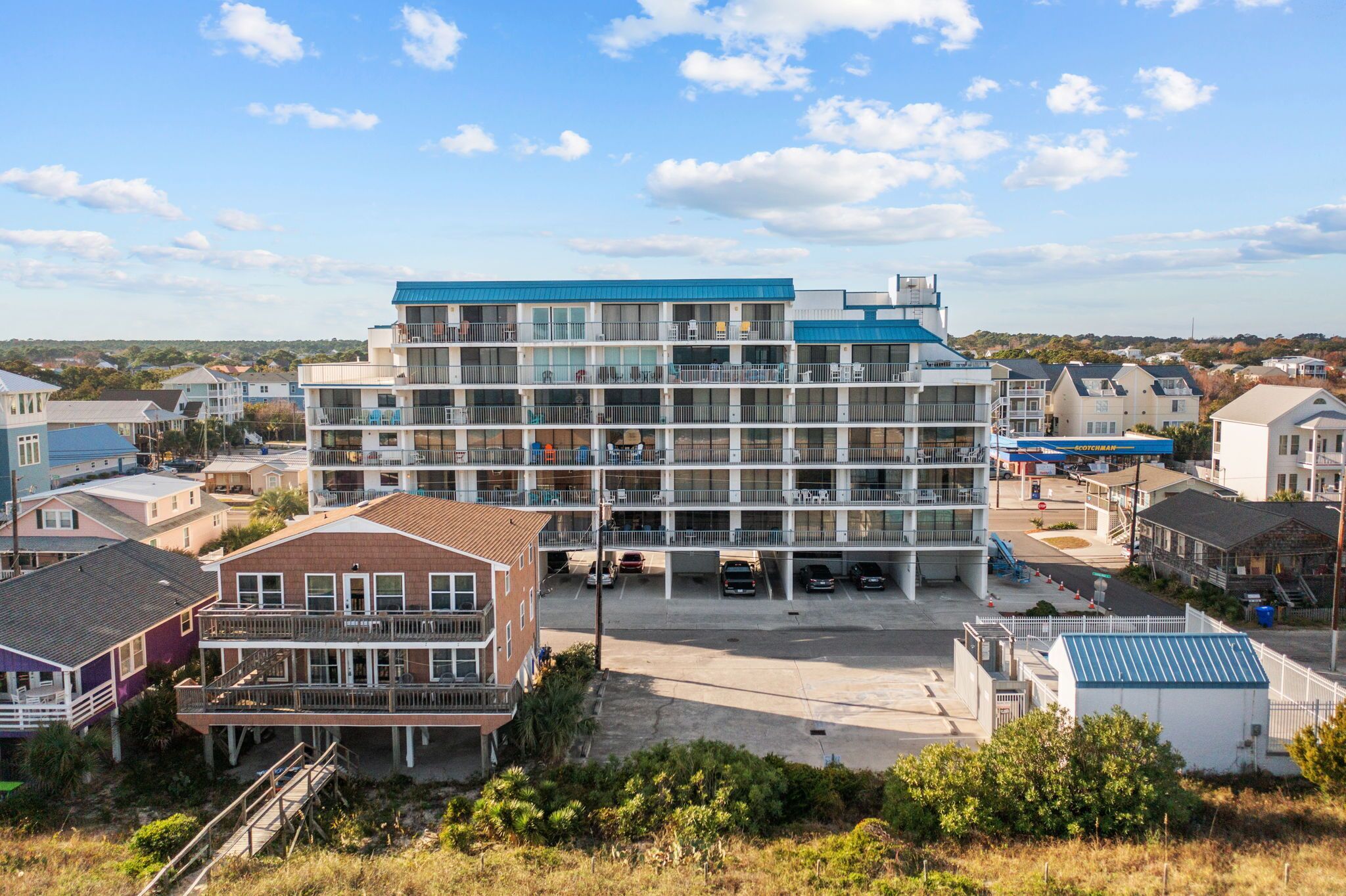 A multi-story hotel with a central courtyard, balconies, and a parking area.
