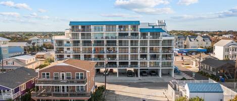 A multi-story hotel with a central courtyard, balconies, and a parking area.