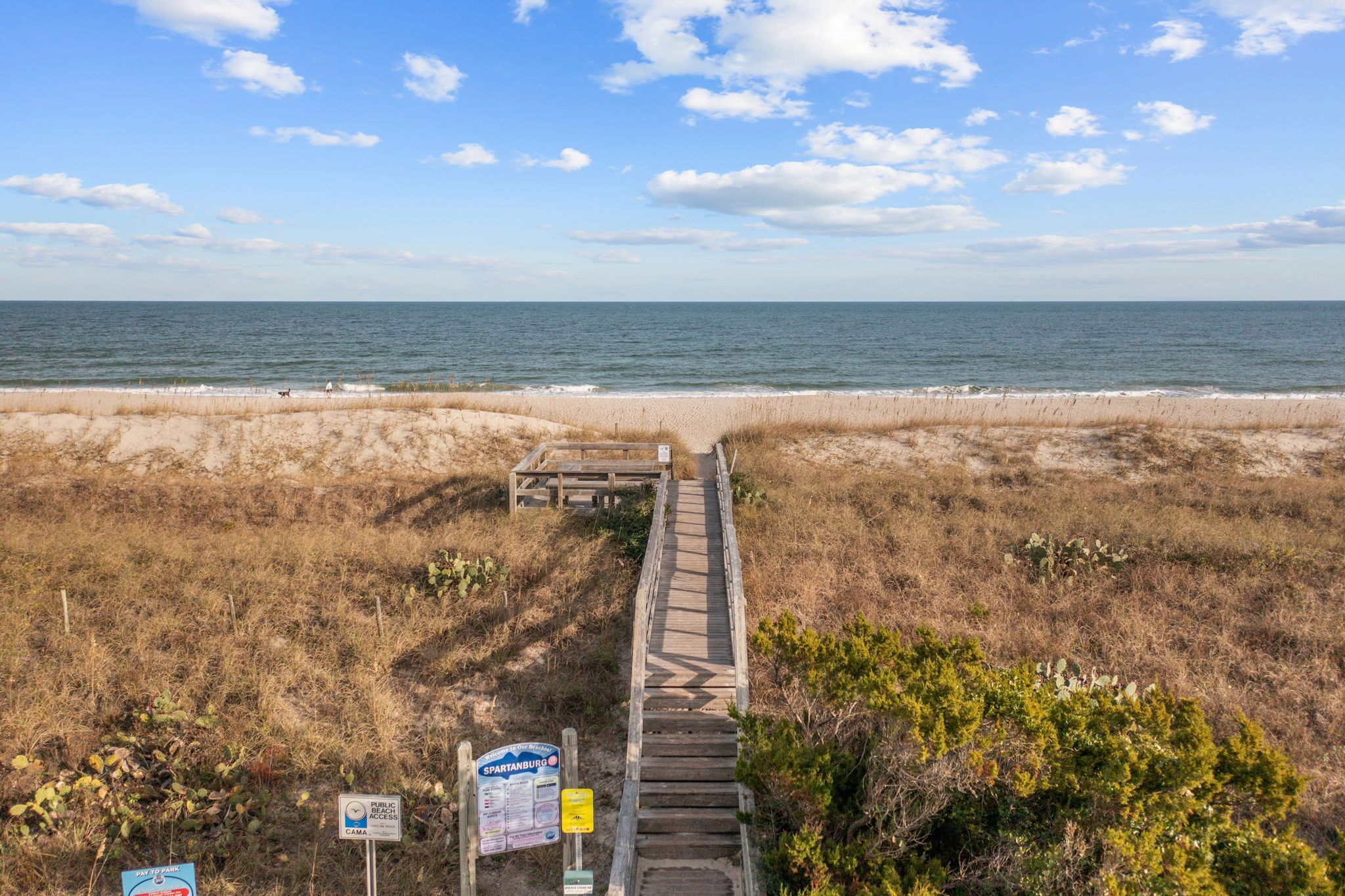 A wooden boardwalk leading to a beach with a clear view of the ocean.