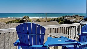 A beach view with blue Adirondack chairs and a wooden deck. - CB Seabee #2 by Carolina Retreats (Carolina Beach)