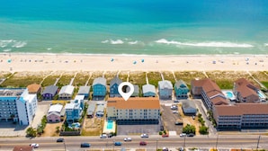 Vista aérea de um hotel à beira-mar, com vários edifícios, uma praia ao fundo e uma visão ampla do oceano.