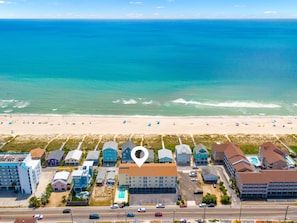Luchtbeeld van een kusthotel met meerdere gebouwen, een strand op de achtergrond en een helder uitzicht op de oceaan.