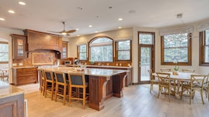 A spacious kitchen with a large island, wooden cabinets, and a dining area with a table and chairs. - Cozy Edwards Retreat w/ Fireplace, Near Ski Resort Osprey Nest by Avantstay (Edwards)