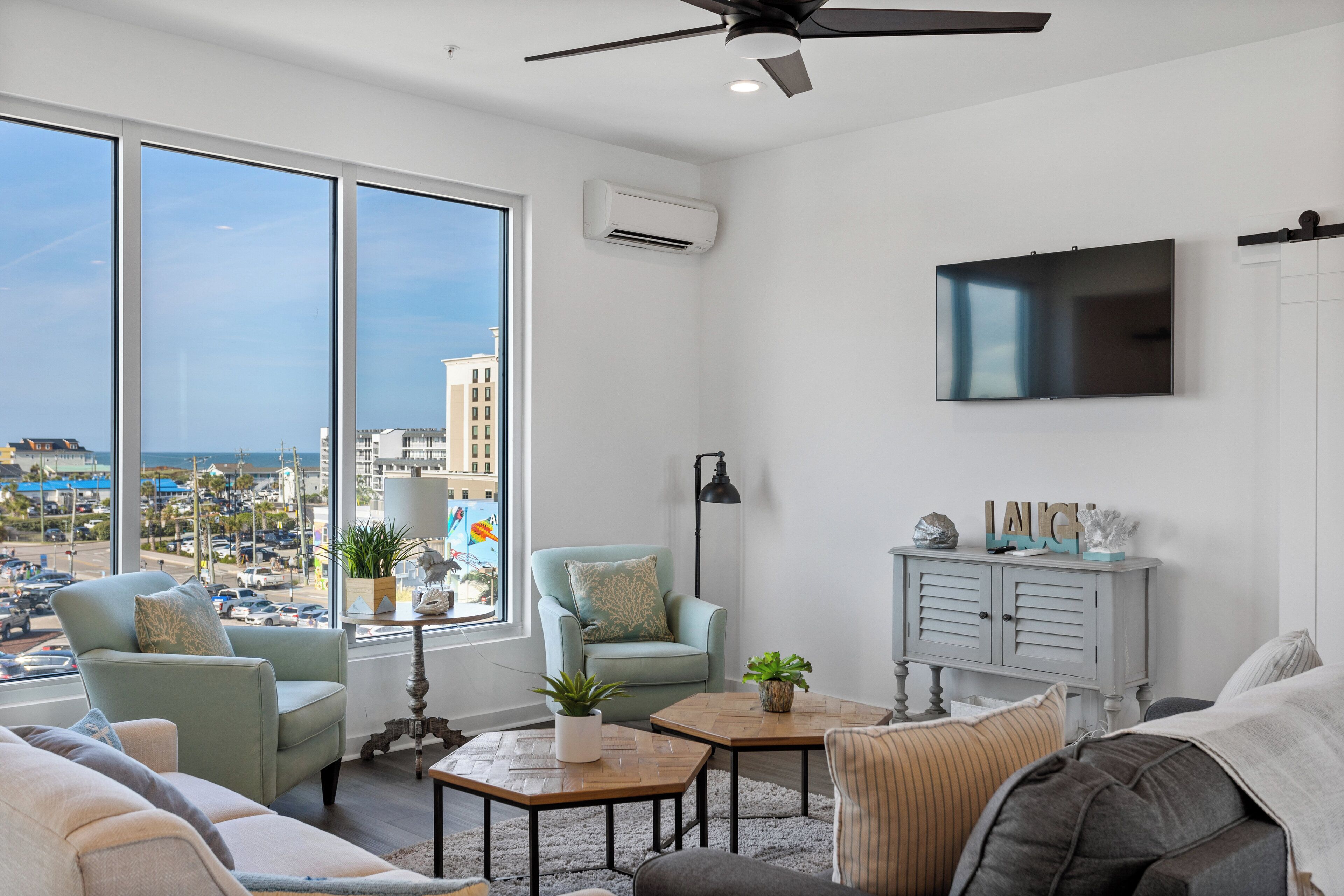 A modern living room with large windows, a flat-screen TV, and a view of the city.