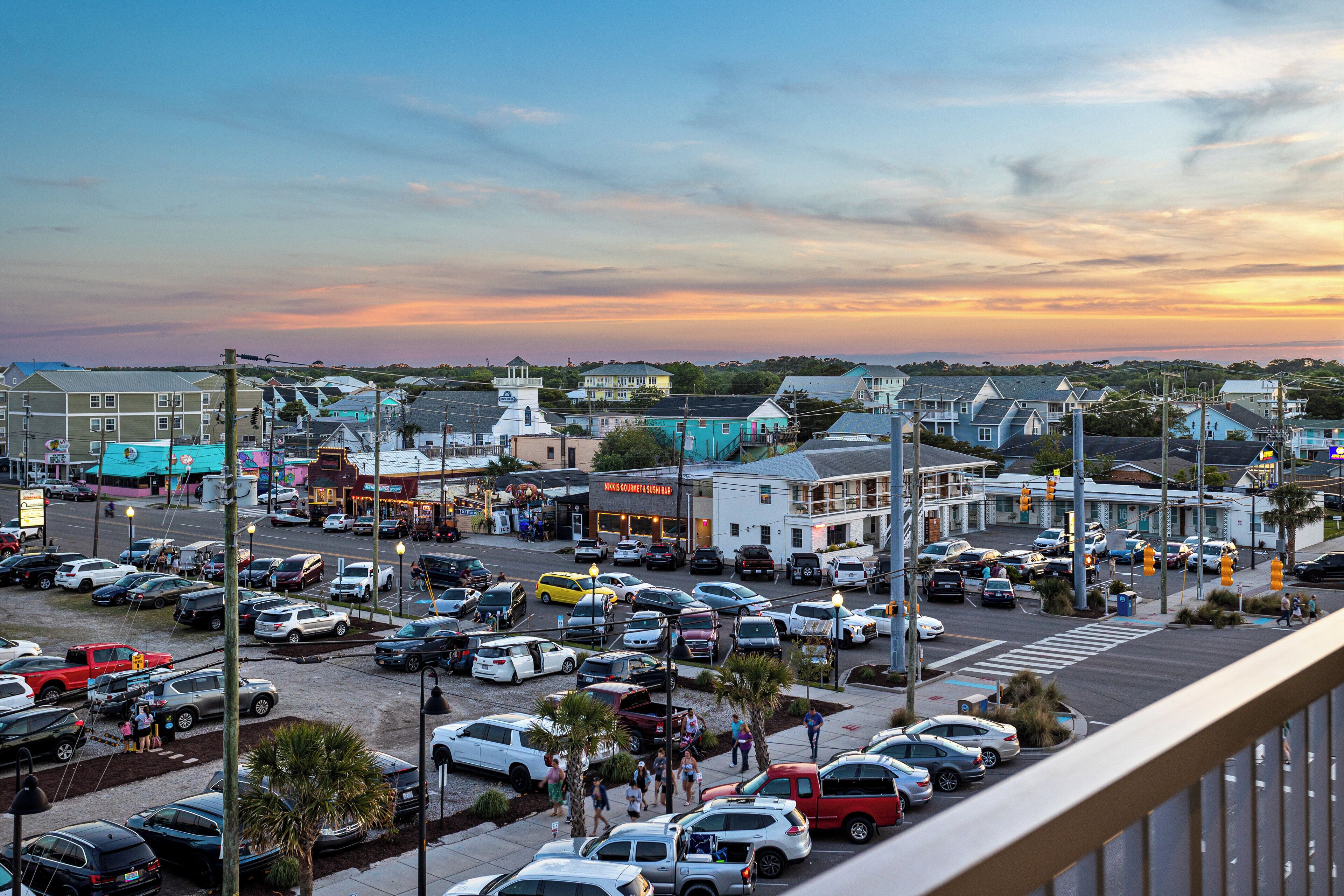 A parking lot with multiple cars and pedestrians.
