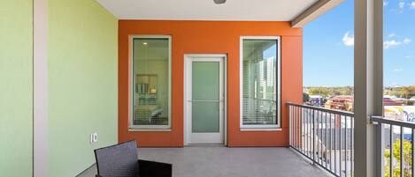 Een balkon met een plafondventilator, een deur en twee ramen.
