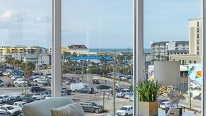 A view from a window overlooking a busy street with buildings and a beach in the background. - Boardwalk Pent House by Carolina Retreats (Carolina Beach)