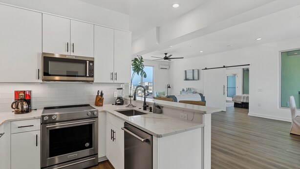 A modern kitchen with stainless steel appliances, a dishwasher, and a large island. - Boardwalk Pent House by Carolina Retreats (Carolina Beach)