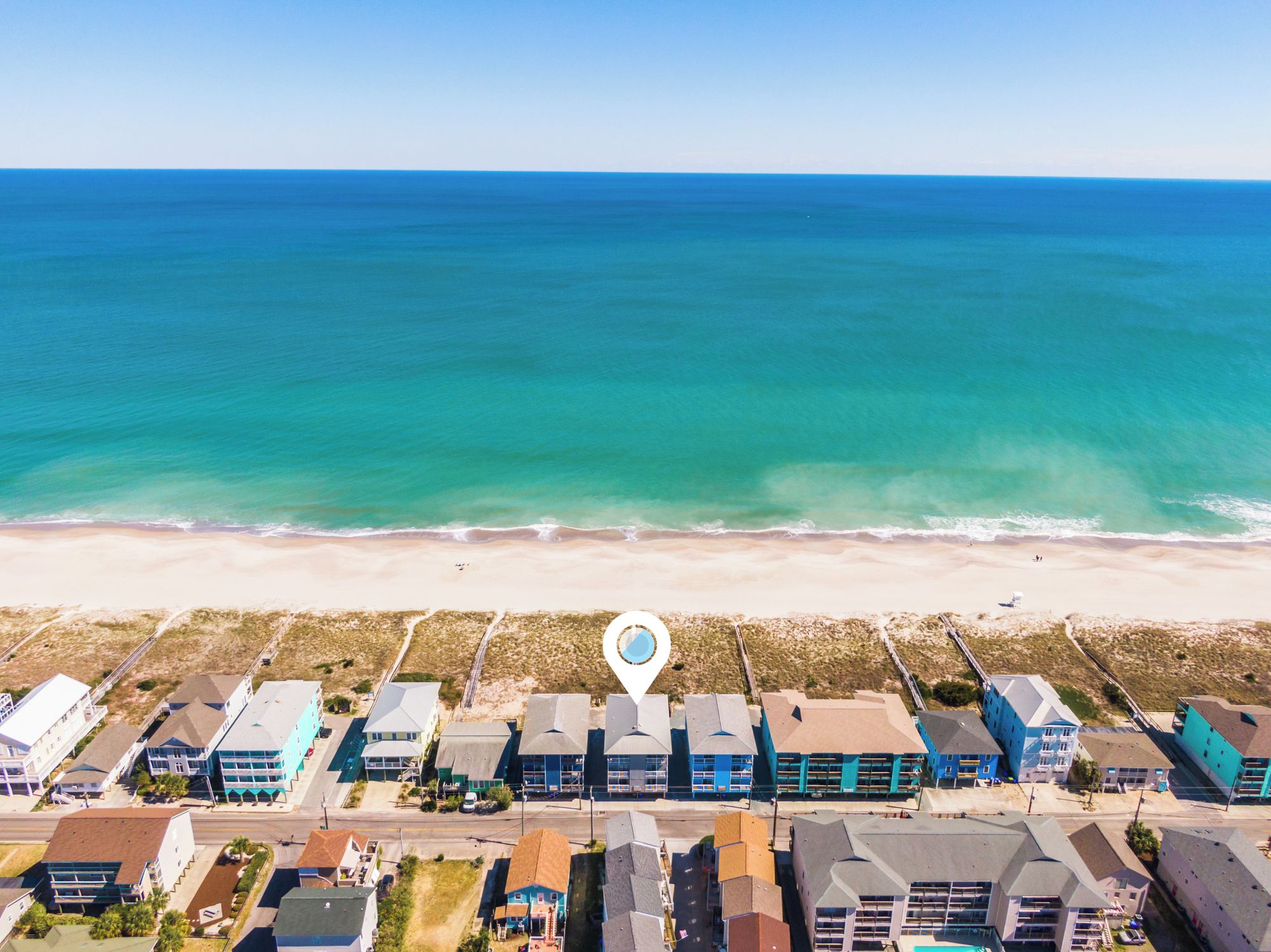 An aerial view of a coastal area with a beach and a row of buildings.