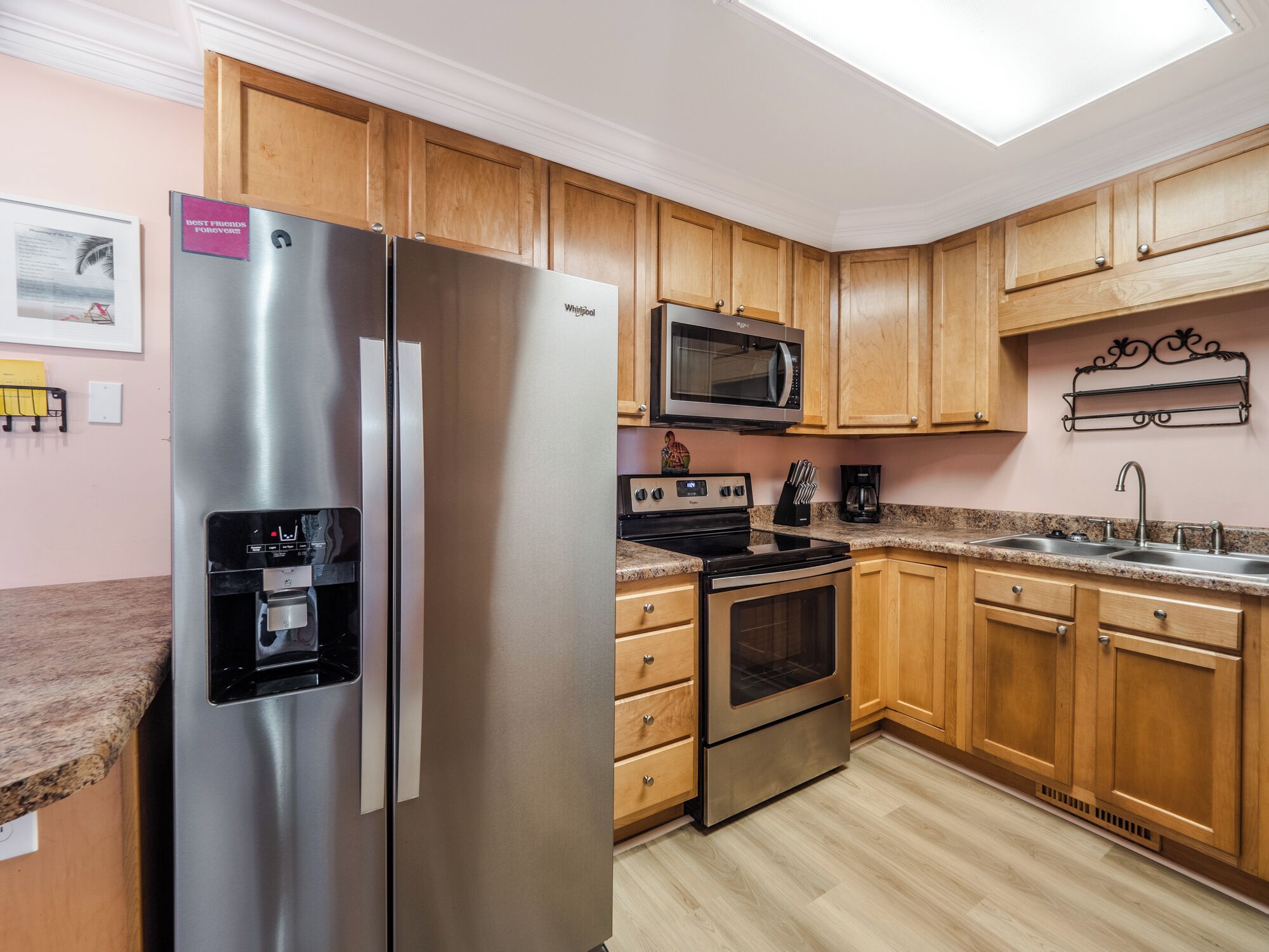 A kitchen with wooden cabinets, stainless steel appliances, a microwave, a refrigerator, and a granite countertop.