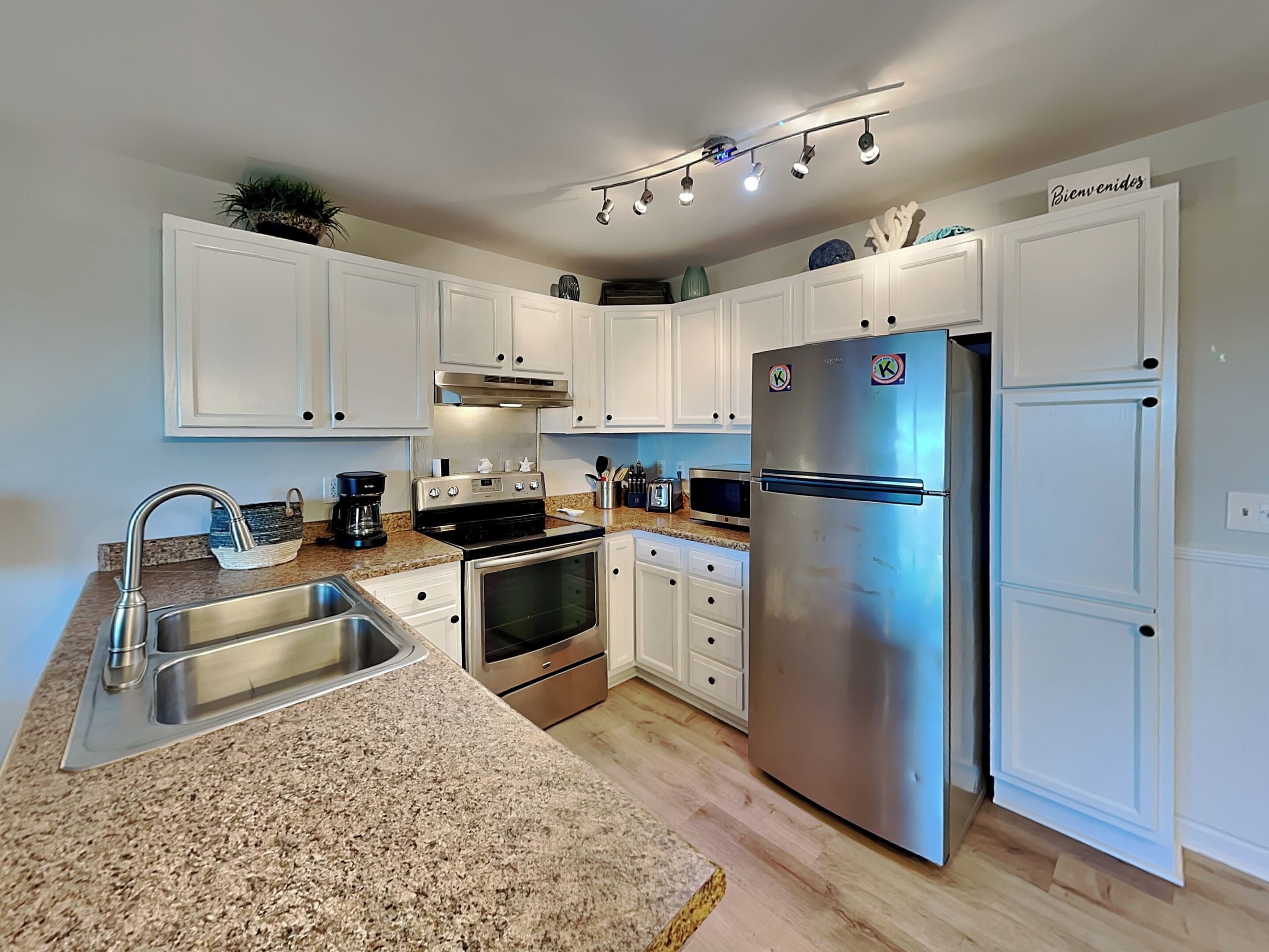 A modern kitchen with white cabinets, stainless steel appliances, granite countertops, and a built-in oven.