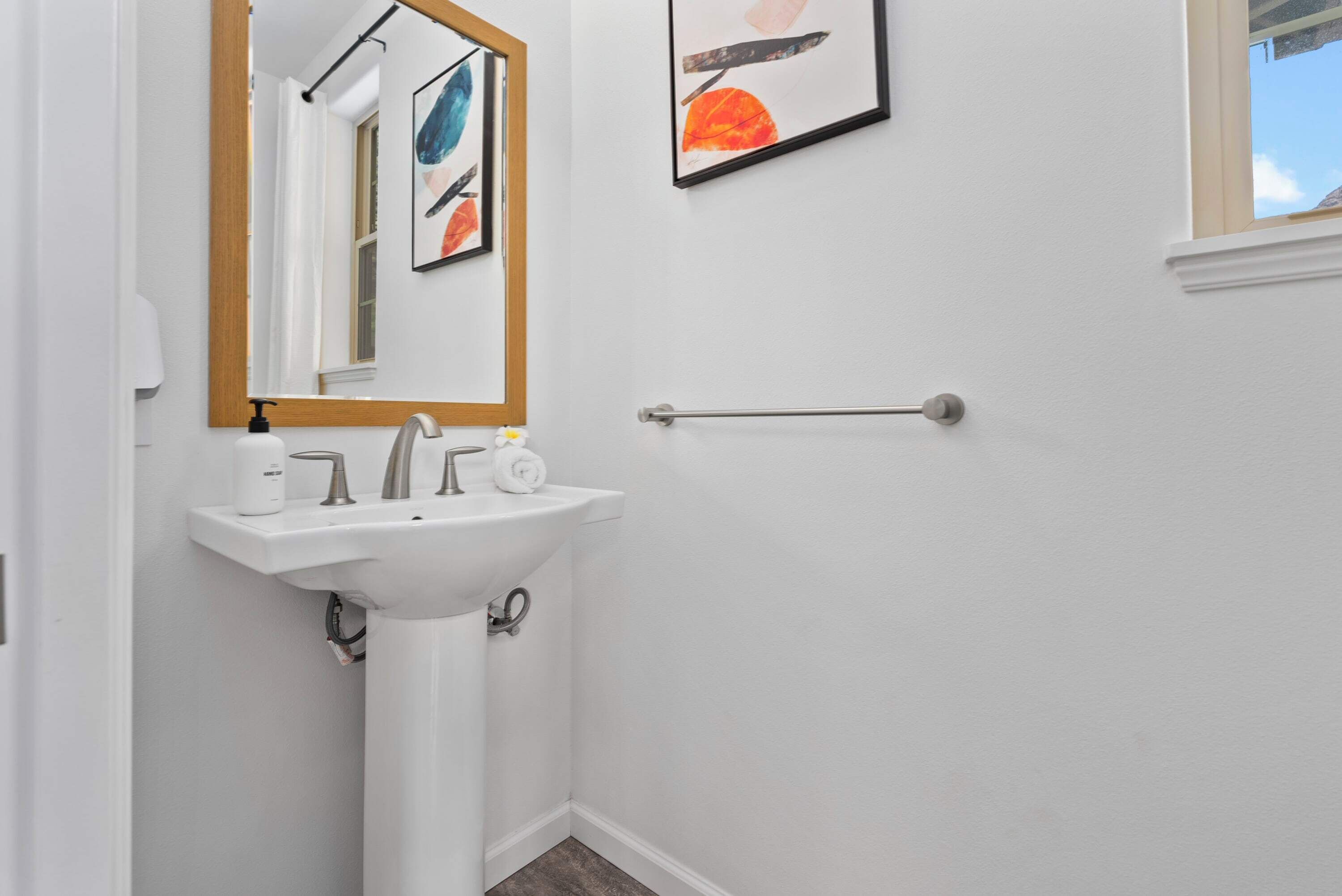 A bathroom with a white sink, a mirror, and a towel rack.