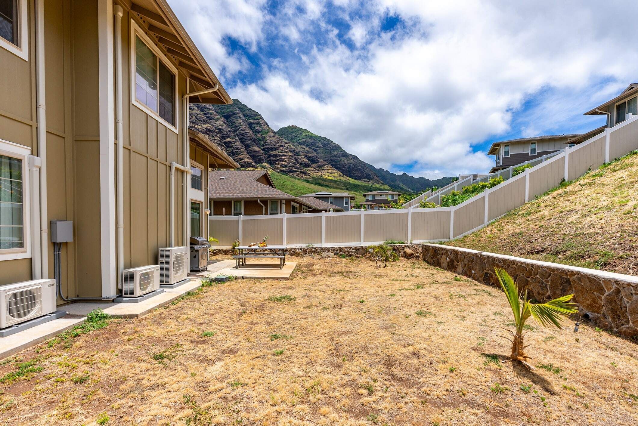 A residential building with a covered patio area, air conditioning units, and a view of a mountainous landscape.