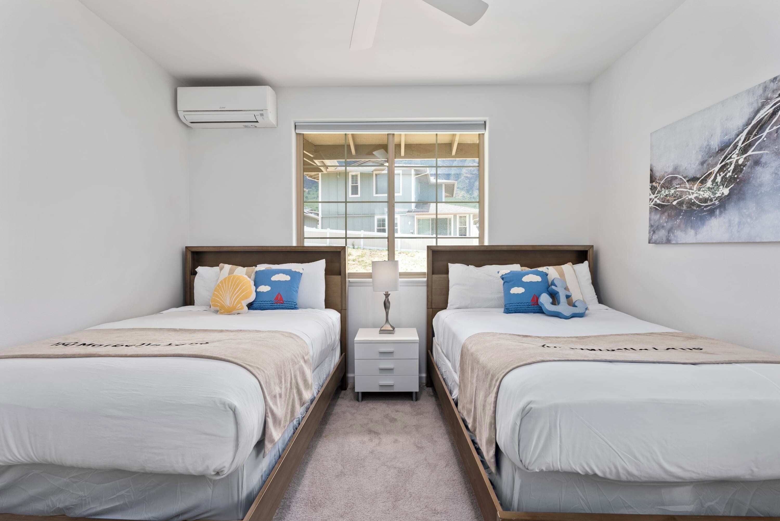 A twin bedroom with two beds, a window with a view, a small bedside table, and an air conditioning unit.