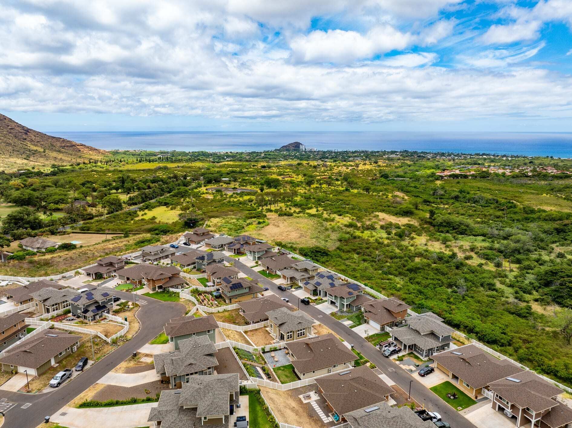 A residential area with houses, roads, and a distant view of the ocean.