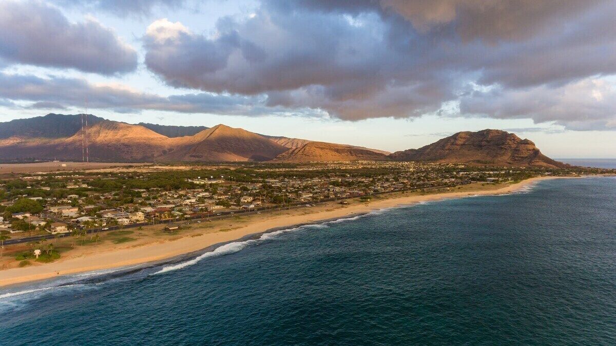 Un pueblo costero con playa, montañas y cielo despejado.