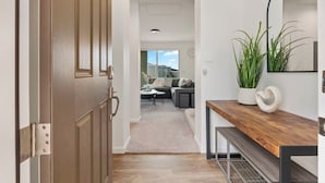 A hallway leading to a living area with a sofa, a coffee table, and a plant on a wooden console table. - @ Marbella Lane - Stunning Gem w/ MT & Ocean Views (Waianae)