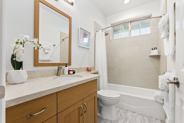 Un baño moderno con lavabo, espejo, inodoro y bañera.